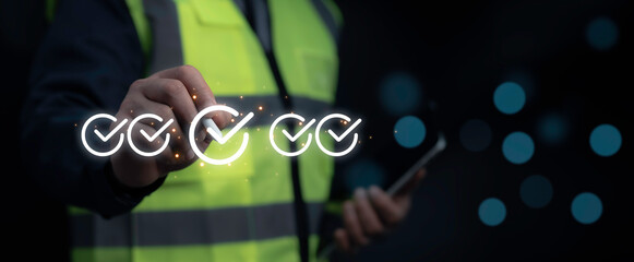 Worker in a high-visibility vest marking a safety checklist in a digital interface symbolizing compliance verification and security assessment
