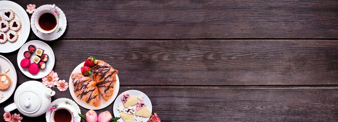 Mother's Day tea corner border over a dark wood banner background. Assortment of sweet desserts and...