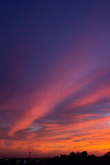 Breathtaking sunset with vibrant hues of orange, red, and purple painting the sky. The silhouetted trees and distant antenna create a serene and dramatic evening landscape