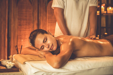 Fototapeta premium Caucasian woman customer enjoying relaxing anti-stress spa massage and pampering with beauty skin recreation leisure in warm candle lighting ambient salon spa at luxury resort or hotel. Quiescent