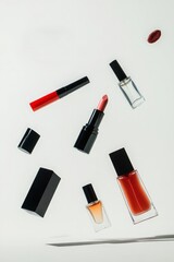 Obraz premium Floating makeup and perfume products against a white background. Items include lipsticks, lip gloss, nail polish, and perfume bottles. Black packaging is a prominent feature