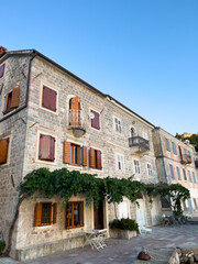 Naklejka premium Old stone building with wooden shutters on the windows and green ivy