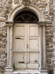 Old white wooden door in the stone facade of the building