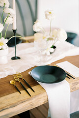 Black plate stands on a white napkin near the menu on a festive wooden table