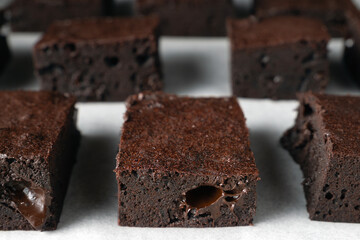 A close up of a chocolate brownie. The brownies are arranged in a rows on a white surface