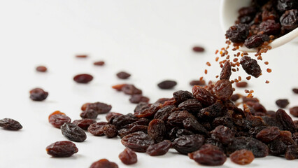 Dried Raisins Falling From Bowl Against White Background