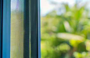 Close up of window screen mesh with blurred green outdoor background for home protection and ventilation