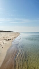 Gentle wave laps shoreline under a vast sky with golden morning light