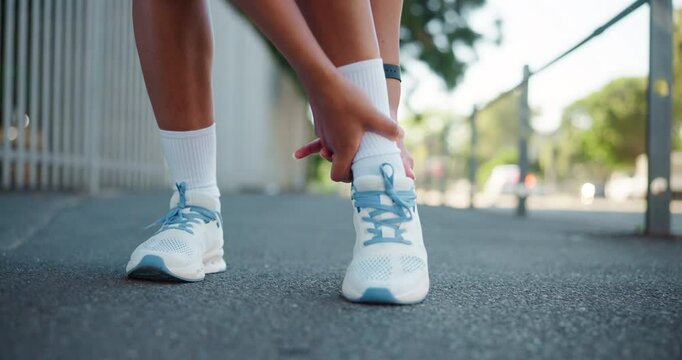 Runner, hands and ankle pain on street with injury, fatigue and sprain with inflammation in city. Person, athlete and shoes for fitness, workout and exercise with joint ache and stress on sidewalk