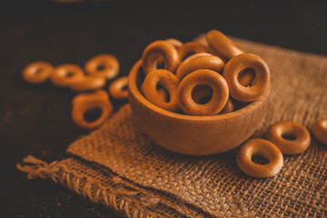 Crispy round bagels in a wooden bowl on rustic burlap fabric. Traditional Eastern European snack...