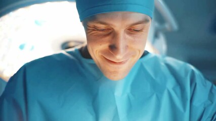 Smiling surgeon performing medical procedure in modern operating room under bright surgical lights, professional healthcare doctor wearing blue scrubs and mask during surgery, hospital medicine treatm