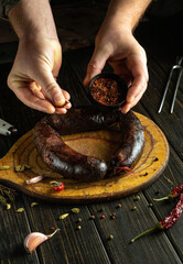 Adding spices by hand to baked blood sausage. The Latin American national dish is prepared on the...