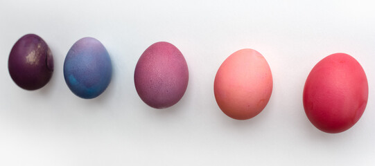 Easter eggs in purple and pink shades are lying on a white background with a shadow photo