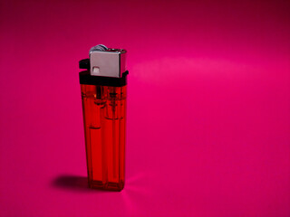 Red plastic cigarette lighter on red paper background