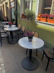 City cafe tables decorated with heather and pumpkins in autumn style standing outside