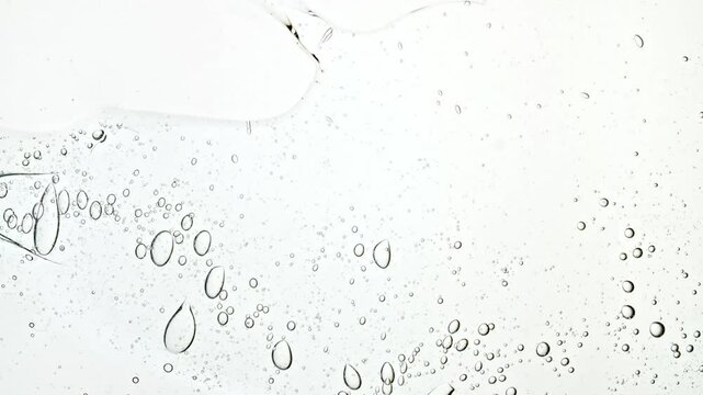 Transparent cosmetic gel fluid with molecule bubbles oil distribution on a white background. Macro Shot of Natural Organic Cosmetics, Medicine. Production Close-up. Slow Motion. High quality 4k.