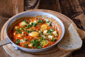 Breakfast shakshuka in frying pan on wooden board table