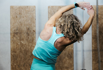 Back view of woman doing side stretch at gym