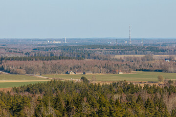 Expansive countryside view showing dense coniferous forest in the foreground, golden and green...