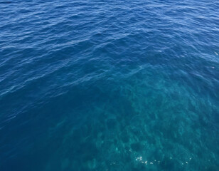 Obraz premium Ocean water surface with gentle waves, deep blue tones, sunlight shimmering on the surface, high-detail photography