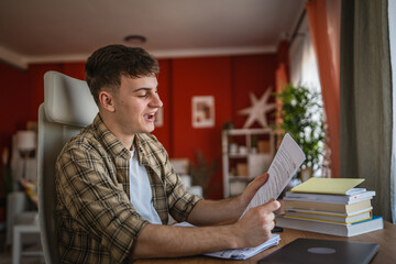 Fototapeta premium young man student study for exam from notes and books at home