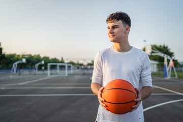 Fototapeta premium One caucasian teenager stand on basketball court with ball