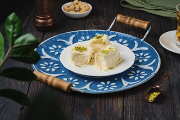 Eastern sweet, pishmaniye or cotton halva with pistachios on a white plate on a dark wooden background. Sweets from around the world.