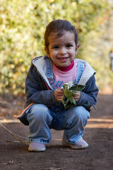 happy cute girl smiling and walking in the garden enjoying the nature at sunny day and green trees
