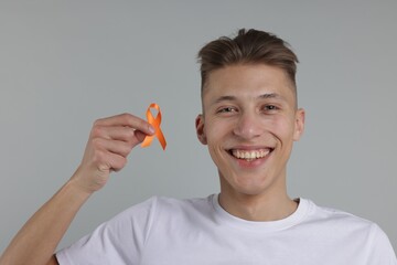 Multiple Sclerosis awareness. Man with orange ribbon on light grey background