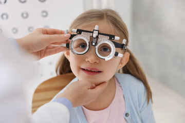 Ophthalmologist examining patient's vision with trial frame indoors, closeup