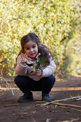 happy cute girl smiling and walking in the garden enjoying the nature at sunny day and green trees