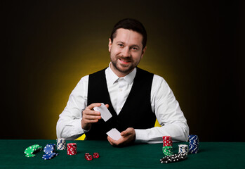 Professional croupier shuffling cards at gambling table on dark yellow background