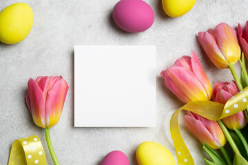 Happy Easter greeting card mockup, colored easter eggs and fresh tulips flowers, blank paper card mock up with copy space