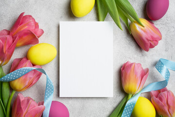 Easter greeting card mockup, white blank paper card with easter eggs and fresh tulips flowers decor, copy space