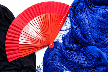 Red fan with blue and black flamenco shawls on white background