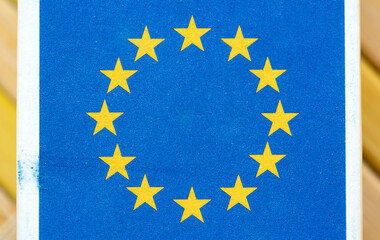 Macro closeup of European Union flag printed on textured paper blue background with twelve yellow stars in a circle. Europe, official EU emblem printed on a EU-made product packaging concept, nobody