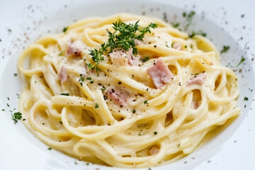 Classic carbonara pasta with a creamy sauce and garnished with fresh herbs