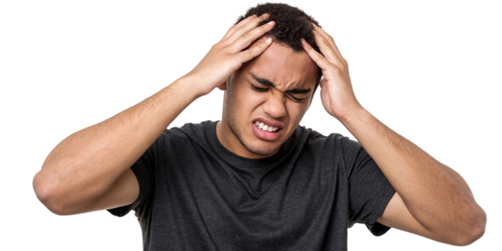 Stressed Young Man Holding His Head in Pain - Concept of Headache, Anxiety, and Mental Strain