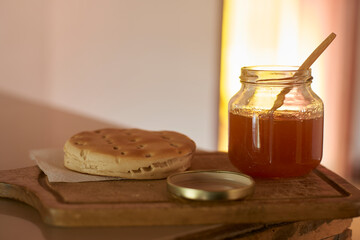 Golden arepa nestled on textured napkin near honey jar, wooden spoon alongside, presenting appetizing venezuelan breakfast or snack setting