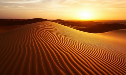 Naklejka premium Golden light paints the rippled sand dunes of a vast desert landscape during a vibrant sunset.