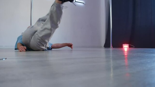 A man is practicing a dance vogue in high heels in front of a mirror in a dance class. Slow motion