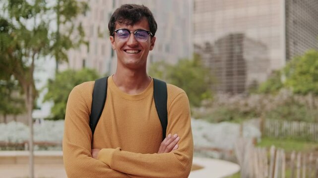 Portrait of European young man, cute geeky male studet smiling outdoors with blured urban background