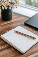 Minimalist workspace with a notebook, pen, and vibrant flower vase on a wooden desk