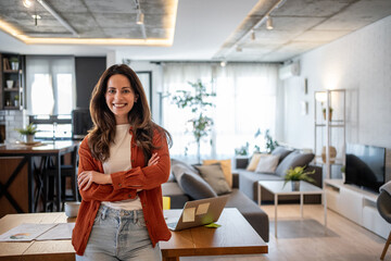 Confident businesswoman smiling with crossed arms in modern home office