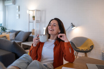 Happy freelancer woman drinking coffee working from home office