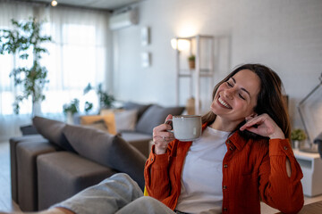 Happy woman drinking coffee at home in living room