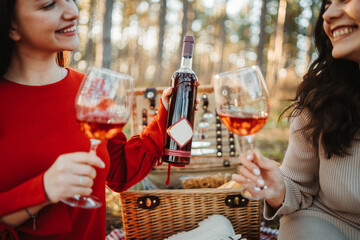 Two young caucasian woman have picnic drink wine in the forest	