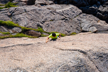 young man freeclimbing up or bouldering, rockclimbing the rock outdoor