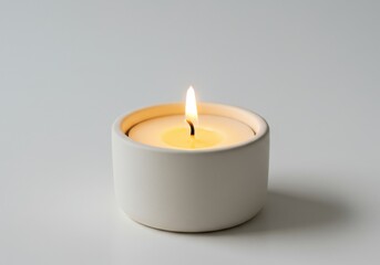 Lit tealight candle with warm yellow flame in a white ceramic holder on a pure white background