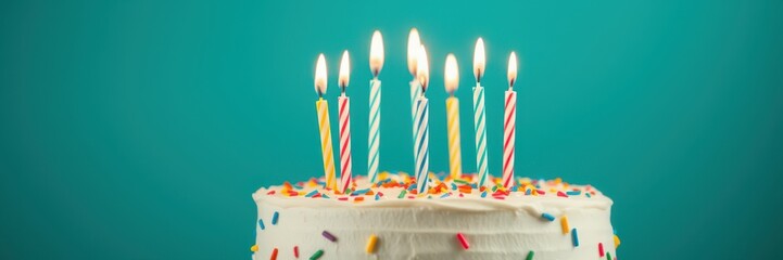 Colorful birthday cake with lit candles and sprinkles set against a bright blue backdrop